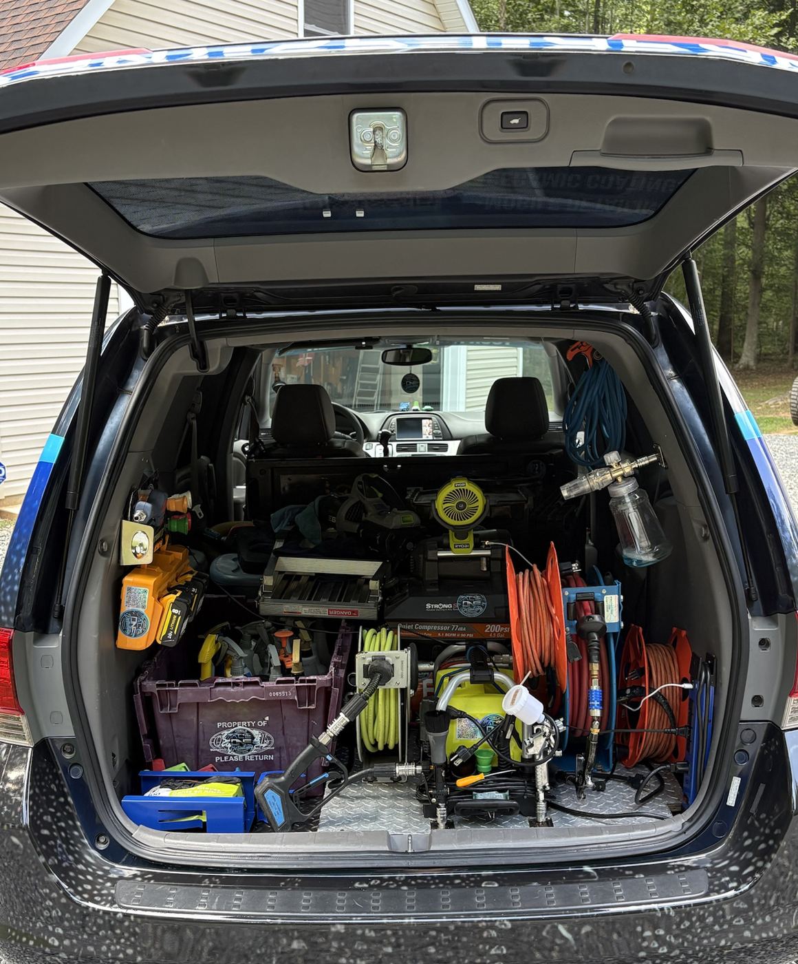 The back of the van packed with hose reels, a compressor and detailing tools
